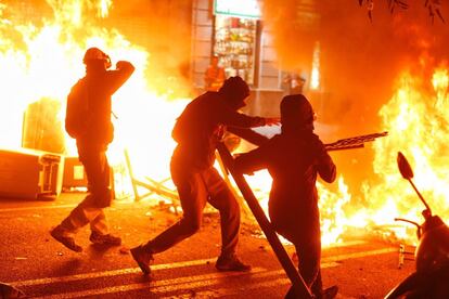 Three protesters throw objects into a bonfire during a demonstration in Barcelona.