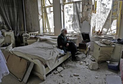 Mohammad Mohiedine Anis, de 70 años, fuma su pipa sentado en su dormitorio destruido mientras escucha música en el tocadiscos, en el barrio de al-Shaar, en Alepo (Siria).