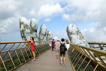 Los turistas que visitan los montes de Ba Na, en el centro de Vietnam, pueden sentirse sujetos por los dioses al pasear por el Puente de Oro, una pasarela colgada del abismo y sostenida por enormes manos abiertas hacia el cielo que parecen brotar de la montaña.