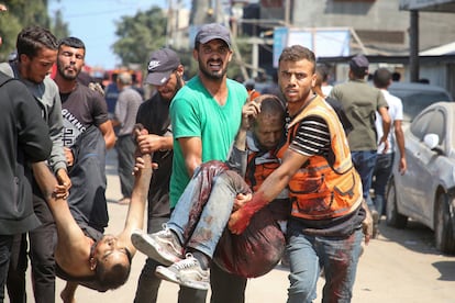 Varias personas trasladan a dos heridos tras un bombardeo israelí sobre Al Mawasi, este sábado. 