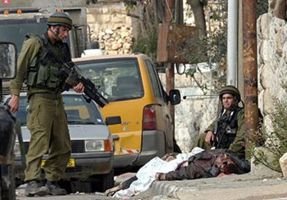 Dos soldados israelíes, ayer, ante el cadáver de un palestino muerto de un disparo en la cabeza durante la ofensiva israelí contra Ramala.