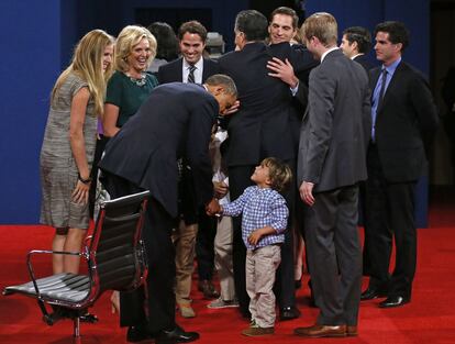 Obama saluda a uno de los nietos de Mitt Romney, mientras éste se abraza con sus hijos.