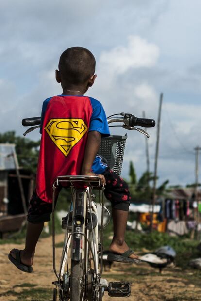 El hijo pequeño de Sandar, de tres años, espera a su madre sentado en la bicicleta vestido con un traje de Superman. Van al centro de detención de Mae Sot a visitar a su padre. "Me gustaría que mis hijos no tuviesen que trabajar tanto como yo", dice Sandar. "Me gustaría que estudiasen y fuesen médicos o contables".