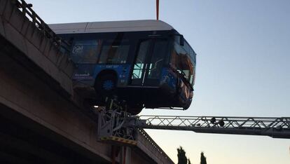 Los bomberos aseguran la parte del autobús que ha quedado colgado del puente.