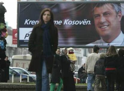 Ciudadanos de Pristina caminan frente a un cartel electoral del Partido Democrático de Kosovo.