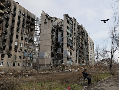 A local resident sits in front of apartment blocks destroyed in the course of Russia-Ukraine conflict in Mariupol, Russian-controlled Ukraine, February 5, 2023. REUTERS/Alexander Ermochenko