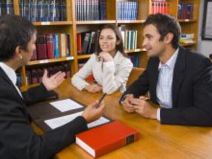 Una pareja consulta a un profesional en un despacho.