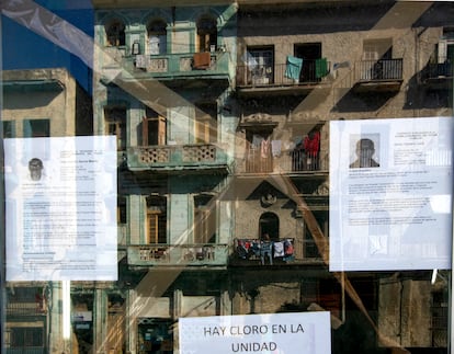 Reflejo de la fachada de un edificio en el escaparate de una tienda donde hay colgadas dos biografias de delegados a diputados de la Asamblea del Poder Popular.