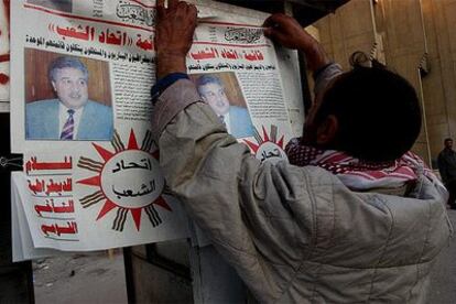 Un hombre pega un cartel con la lista de los candidatos de Comunidad Unida, liderado por el comunista Majeed Hameed.