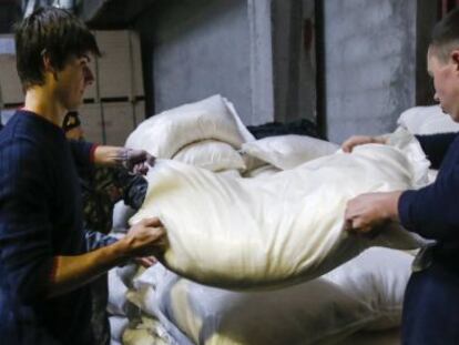 Dois homens levantam um saco com ajuda humanitária em Makeyevka, na região de Donetsk.