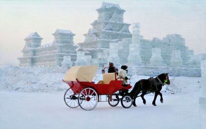 Un carruaje pasa ante un edificio de hielo en la ciudad de Harbin, al noreste de China. 