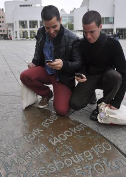 En la imagen, dos jóvenes españoles hacen una foto de una placa que indica la distancia entre Ulm y Madrid en la plaza de la catedral de Ulm, Alemania. EFE/Archivo