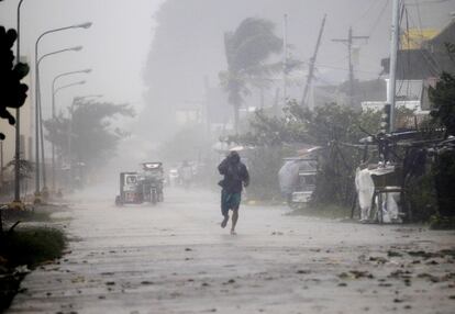 Un hombre camina por una de las calles de la ciudad de Atimonan, en la provincia de Quezon, barrida por los fuertes vientos provocados por el tifón que ha barrido el país.Según la ONU, más de treinta millones de filipinos se verán afectados por las inundaciones causados por Hagupit.
