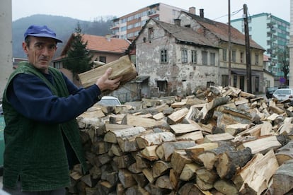 Un vecino hace acopio de leña para el invierno en la ciudad de Gorazde, Bosnia-Herzegovina. Los combates entre serbios y bosnios dejaron sus huellas en las casas del fondo.
