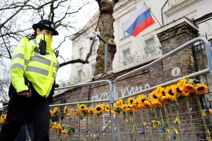 Una oficial de policía pasa junto a los girasoles que los ciudadanos han dejado en el exterior de la Embajada rusa en Londres tras la invasión de Ucrania.