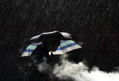 Imagen a contraluz de una mujer que camina bajo la lluvia en Longtoushan, provincia de Yunnan, China.