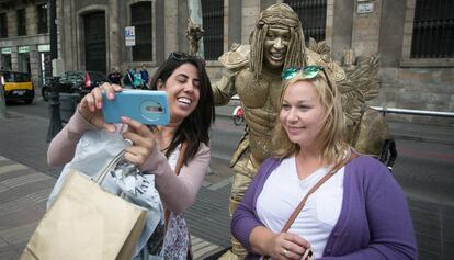 Dos turistas se hacen una foto con una estatua humana.