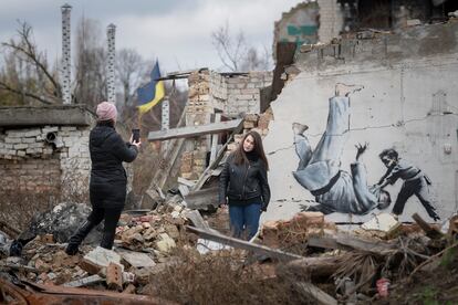 Una mujer se hace una foto frente a un grafiti atribuido a Banksy en Borodianka, Ucrania.
