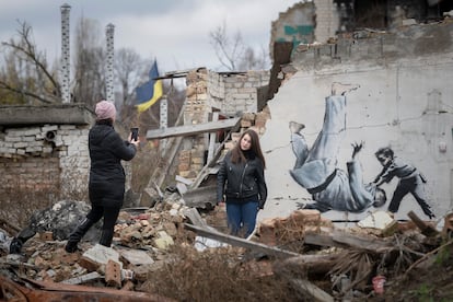 Una mujer se hace una foto frente a un grafiti atribuido a Banksy en Borodianka, Ucrania.