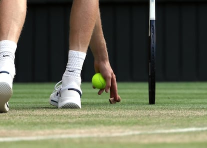 Jannik Sinner recoge el corcho de una botella durante el partido de la final de Wimbledon contra Alcaraz, este domingo.