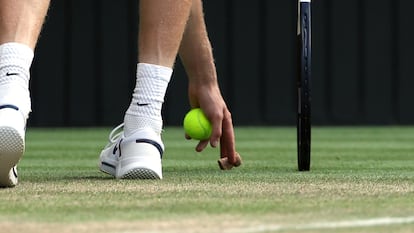 Jannik Sinner recoge el corcho de una botella durante el partido de la final de Wimbledon contra Alcaraz, este domingo.