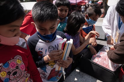 Varios niños eligen libros de la colección en el tianguis.