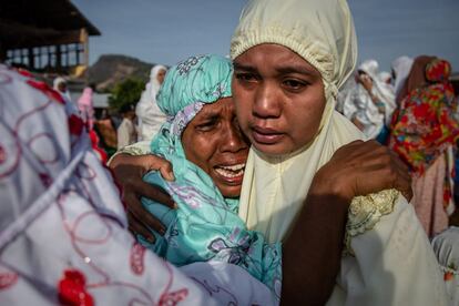 Dos mujeres lloran y se abrazan después de realizan la oración del Eid al-Adha en Pemenang.