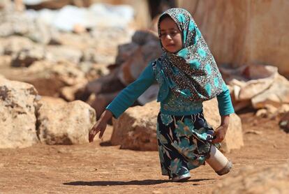 Maya Mohammad Ali Merhi, de ocho años, camina usando piernas protésicas hechas por su padre en latas de un campamento para personas desplazadas, en la provincia de Idlib, en el norte de Siria.