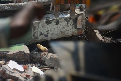 Un cadáver entre los escombros del edificio textil derrumbado en Dacca (Bangladesh). Al menos 110 personas, la mayoría obreros, han muerto al derrumbarse un edificio que albergaba varias fábricas de tejidos.