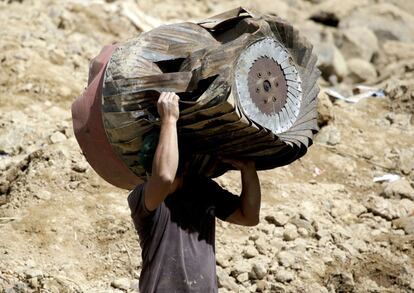 Un minero filipino carga los restos de una estructura que fue aniquilada en el sitio donde se cree que las víctimas fueron sepultadas por un deslizamiento de tierra.