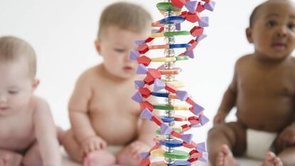 Tres bebés frente a una escultura de ADN.