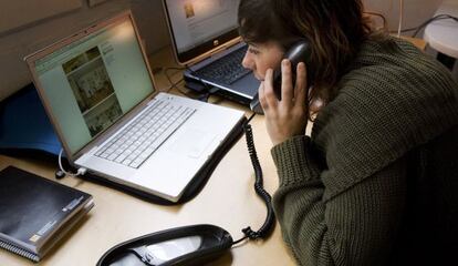 Una mujera habla por tel&eacute;fono mientras consulta Internet