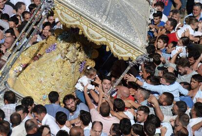 La gente toca la imagen de la Virgen de Rocío durante una procesión, el 10 de junio de 2019. El peregrinaje de El Rocío, el más grande de España, reúne a cientos de miles de devotos con atuendos tradicionales que se trasladan en carruajes decorados a través de la campiña andaluza.