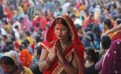 Una mujer reza al dios del sol junto a otros fieles en el río Yamuna, en Allahabad (India).