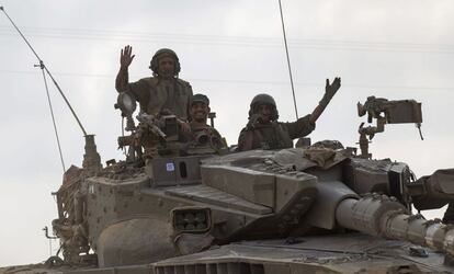 Tres soldados israelíes saludan desde su carro de combate Merkava mientras salen de la Franja de Gaza hacia una posición en la frontera entre Gaza e Israel. El este de Jan Yunis está desde ayer bajo un intenso fuego de los tanques y los aviones israelíes, que han causado el éxodo de la población y causado la muerte a 26 personas, en su gran mayoría civiles, en apenas 24 horas.