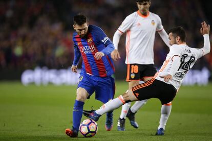 El defensa del Valencia, José Luis Gaya, intenta detener el avance de Messi.