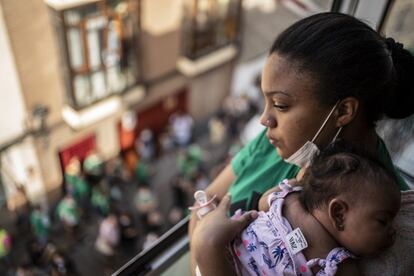 Angélica, de 18 años, y su hija, Adelehin, asomadas en la ventana de su casa mientras decenas de activistas permanecen en la calle para detener el desahucio.