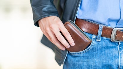 Plano detalle de la mano de un hombre sacando la cartera del bolsillo.