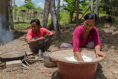 La lideresa con una compañera de su cooperativa ralla el tubérculo de yuca para extraer su almidón.