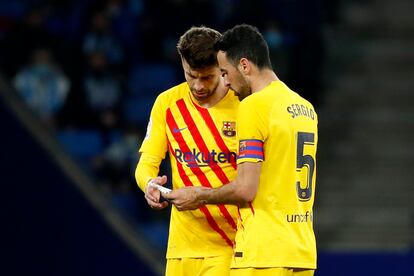 Piqué y Busquets observan el papel que les envió Xavi Hernández con el cambio de sistema.