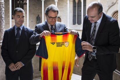 Artur Mas (dentro) recibe una camiseta de la seleccion catalana de futbol.