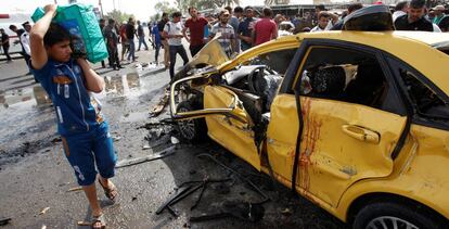 Un joven pasa junto a los destrozos dejados por un coche bomba en el barrio chi&iacute; de Ciudad Sader, en Bagdad.