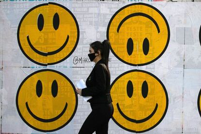 Una mujer pasa frente a un grafiti, en el centro de São Paulo (Brasil). Las dosis de la vacuna creada por el laboratorio chino Sinovac llegaron a la ciudad brasileña de São Paulo, donde está previsto que a partir de hoy comiencen a ser aplicadas a 9.000 voluntarios, todos ellos trabajadores sanitarios.