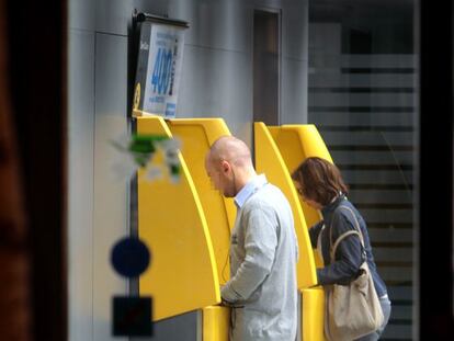 Dos personas operan en cajeros automáticos.