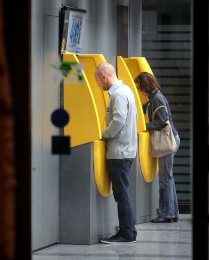 Dos personas operan en cajeros automáticos.