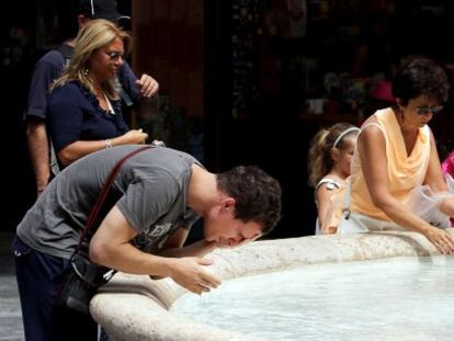 Varias personas se refrescan en una fuente de Valencia.