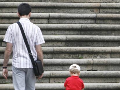 Un padre con su hijo de espaldas ante unas escaleras.