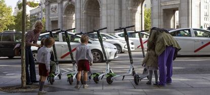 Patinetes eléctricos aparcados en la acera frente la Puerta de Alcalá en Madrid.