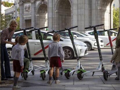 Patinetes eléctricos aparcados en la acera frente la Puerta de Alcalá en Madrid.