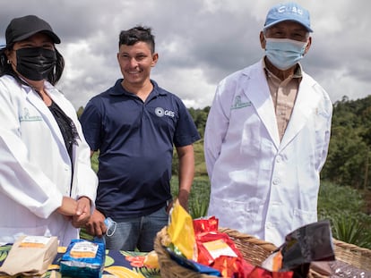 José Luis, un agricultor que fue repatriado a Honduras tras ser detenido en Estados Unidos, junto a dos expositores en una muestra gastronómica y de agricultura en Cerro Verde, Honduras.